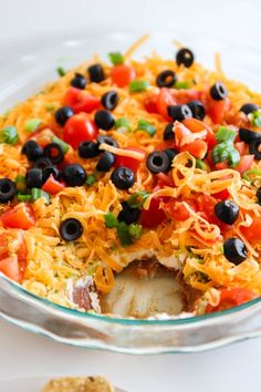 a plastic container filled with black olives, peppers and pasta salad on top of a blue table cloth