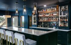 a bar with stools and bottles on the shelves