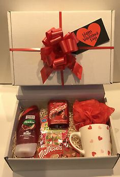 an open gift box filled with chocolates, coffee mug and heart - shaped candy