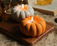 three pumpkin candles sitting on top of a wooden tray