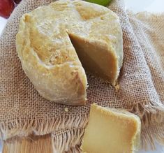 a piece of cheese sitting on top of a wooden cutting board next to an apple