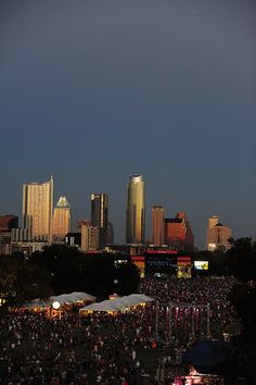 a large group of people standing around in front of a cityscape at night