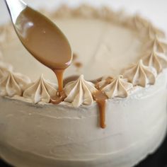 a spoon is pouring caramel sauce onto a cake