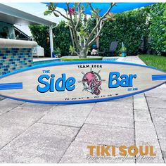 a surfboard sitting on the ground in front of a building with a sign that says the side bar