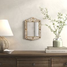 a table with a lamp, vase and mirror on it