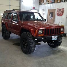 a red jeep is parked in a garage