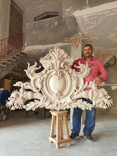 a man standing next to a large white sculpture in a room filled with unfinished walls