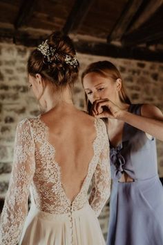 two women in dresses standing next to each other and one is fixing the back of another woman's dress