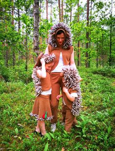 two people dressed up in costumes standing in the woods with pine cones on their shoulders