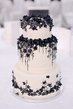 a three tiered cake with black flowers on it