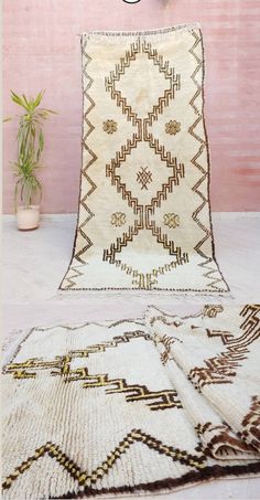 an old rug is sitting on the floor next to a potted plant and pink wall