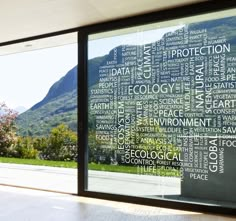 a large window with words written all over it in front of a mountain range and trees