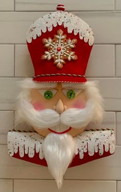 a red and white nutcracker wearing a santa claus hat on top of a brick wall