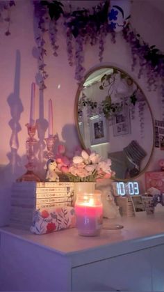 a table topped with a vase filled with flowers next to a mirror and candles on top of it