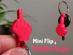 a hand holding a pink plastic keychain with two keys attached to it and the words mini flip j middle finger