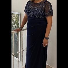 a woman in a blue dress standing on a balcony with her hand on the railing