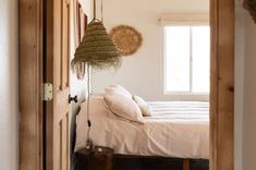 a bed sitting in a bedroom next to a wooden door with two baskets hanging from it