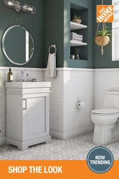 a white toilet sitting next to a sink in a bathroom under a mirror and light fixture