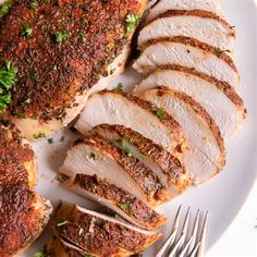 sliced chicken on a white plate with parsley sprinkled around the top and sides