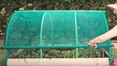 a woman is tending to her baby in the garden with a green fence behind her