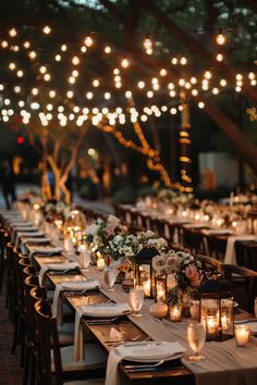 a long table is set with candles and plates for an outdoor wedding reception in the evening