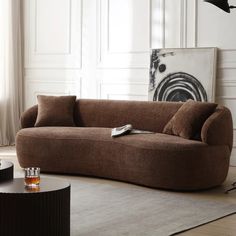 a living room with a brown couch and coffee table in front of a white wall