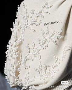 the back of a white shirt with embroidered flowers on it