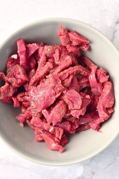 a white bowl filled with meat on top of a table