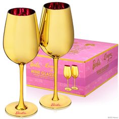 two gold wine glasses sitting next to a pink box