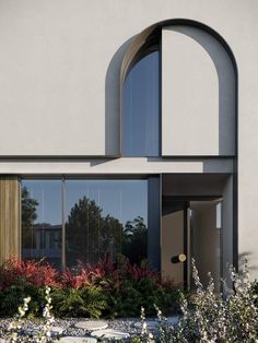 an arched window on the side of a building with plants and flowers in front of it