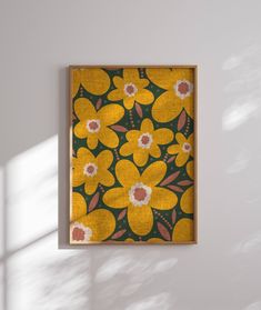 a yellow and green flowered painting hanging on a wall next to a white wall