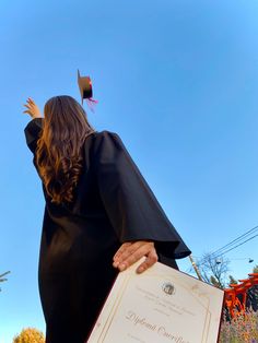 a woman in black graduation gown holding a diploma