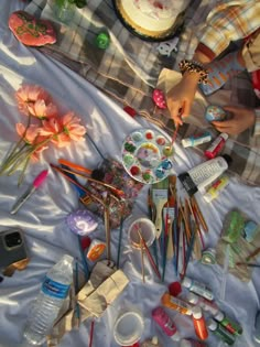 a table topped with lots of crafting supplies on top of a white sheet covered ground