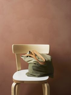 a bag sitting on top of a wooden chair next to a brown and pink wall