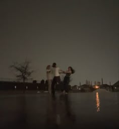 three people standing in the rain at night