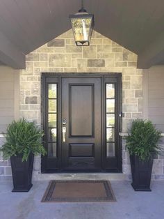 a black door with two planters on either side and a light hanging above it