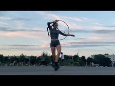 a woman holding a tennis racquet while standing on top of a parking lot