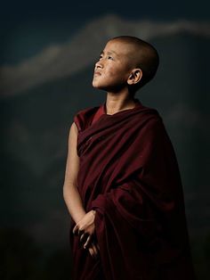 a young monk standing in the dark with his eyes closed