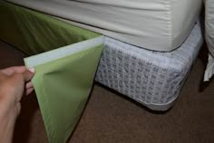 a person is opening up a green piece of cloth next to a bed with white sheets