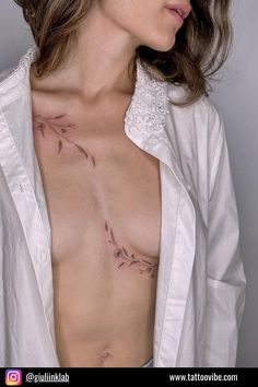 a woman with tattoos on her chest is posing for the camera while wearing a white shirt