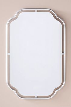 a white square mirror mounted to the side of a wall with a metal frame around it