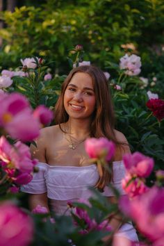 a woman is sitting in the middle of pink flowers with her eyes closed and smiling