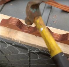 a person is using a hammer to cut through the edge of a piece of wood