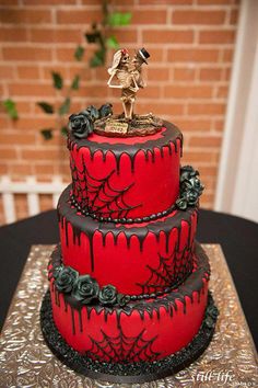 a three tiered red cake with black icing and decorations on the top layer