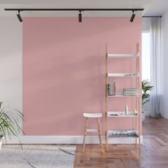 a living room with pink walls and wooden flooring, white furniture and a plant in the corner