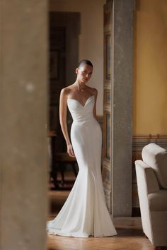 a woman in a white wedding dress posing for the camera