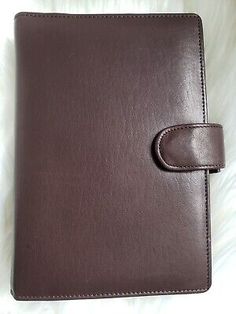 a brown leather notebook with a button on the front, and a white furnishe background