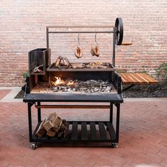 a bbq grill with fire and wood on the side walk next to a brick wall