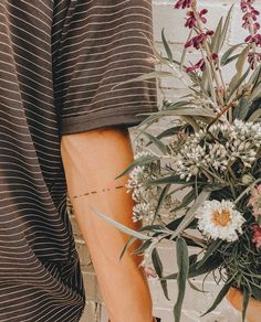 a person holding a bouquet of flowers in front of a brick wall with writing on it