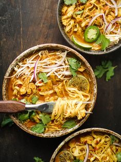 three bowls filled with noodles and vegetables on top of a wooden table